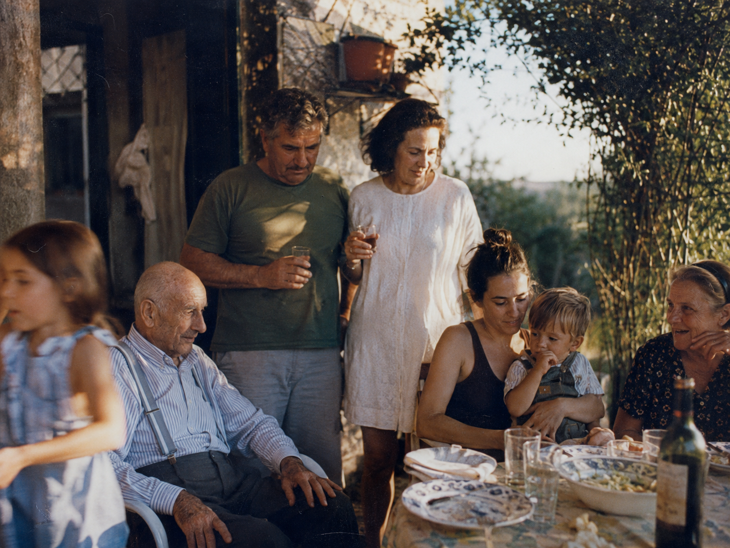 Una familia reunida alrededor de una mesa al aire libre.